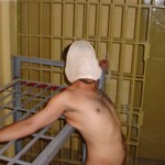 Abu Ghraib: 8:59 p.m., 18 octobre 2003. Un détenu enchainé, nu, à son lit avec une paire de sous-vêtement lui couvrant le visage. (Photo: domaine public)