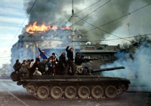 Romanian demonstrators sit on top of a tank as it passes in front of a burning building, December 22 1989, in Bucharest during the 1989 anti-communist revolution. (Photo: Radu Sigheti)